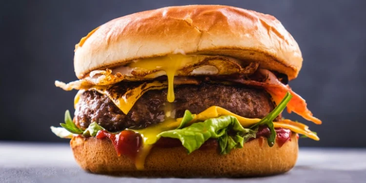 A burger with cheese, salad and sauce